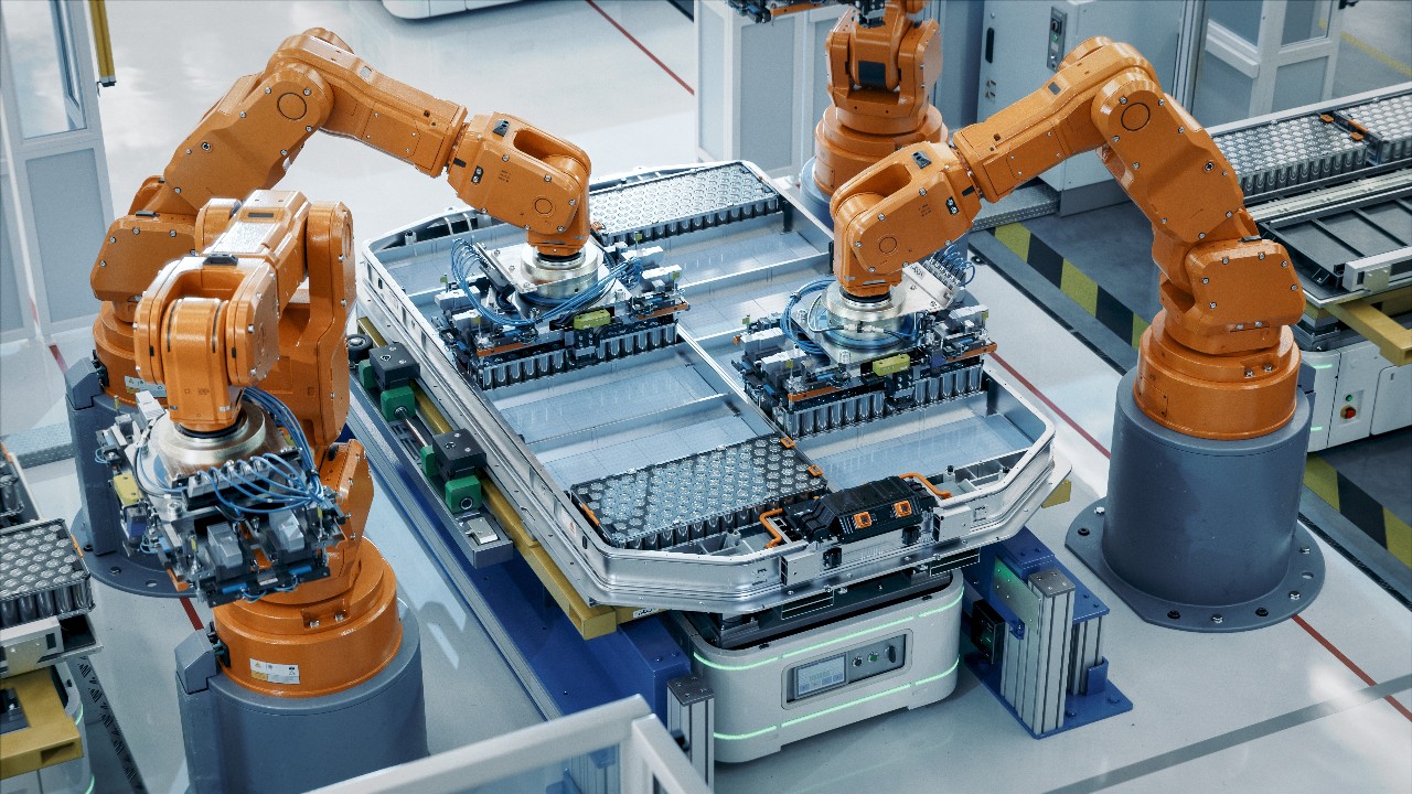 Orange Industrial Robot Arms Assemble Skateboard style EV Battery Pack on Automated Production Line. Electric Car Smart Factory Equipped with Robotic Arms. Battery Module Installation Process Top View